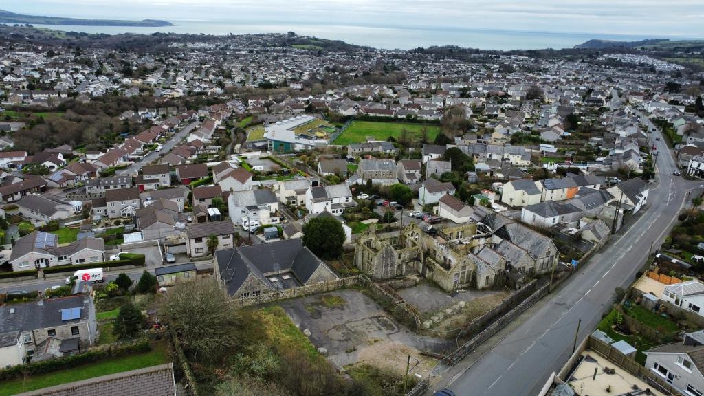 Lot: 56 - SUBSTANTIAL FORMER SCHOOL PREMISES - Aerial photo showing buildings and area of hardstanding with sea in the background